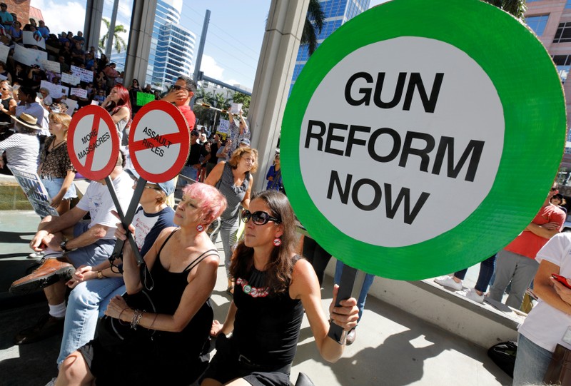 FILE PHOTO: Protesters hold signs as they call for a reform of gun laws three days after the shooting at Marjory Stoneman Douglas High School, at a rally in Fort Lauderdale