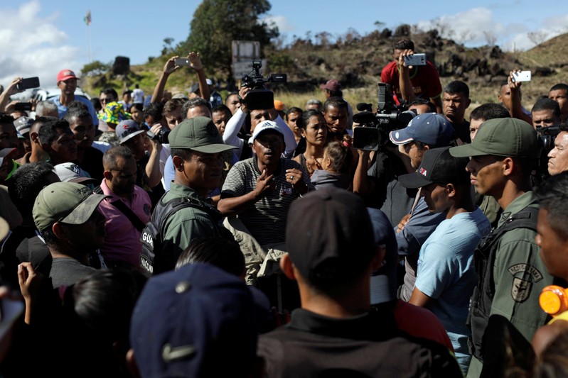 People talk with Venezuelan soldiers at the border between Venezuela and Brazil in Pacaraima
