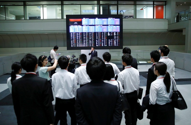 FILE PHOTO - Visitors look at an electronic stock quotation board at the TSE in Tokyo