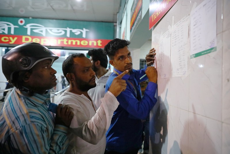 Men look at a list of people who were injured in a fire in Dhaka
