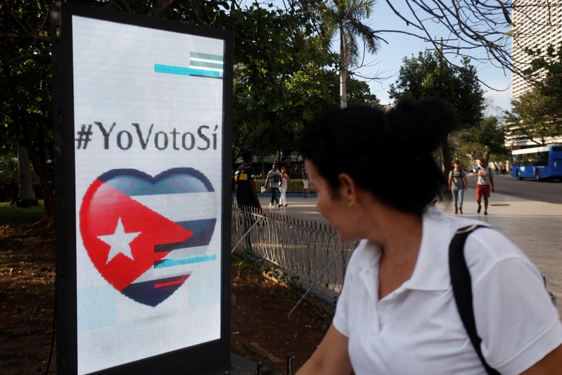 A woman passes by a screen displaying images promoting the vote for 