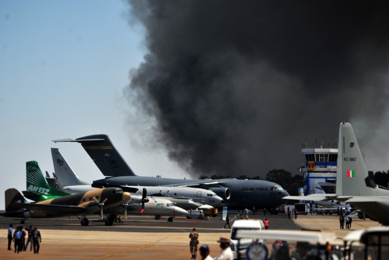 Smoke billows past a row of parked planes after a fire broke out in a parking lot during the Aero India show at the Yelahanka Air Force Station in Bengaluru