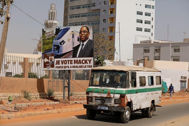A bus drives past a campaign poster for the upcoming presidential election in Dakar