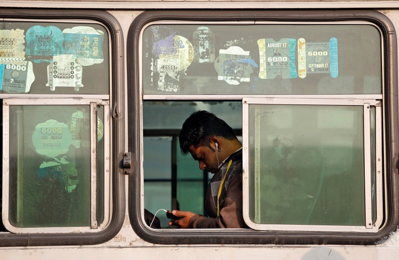 A man looks into his phone as he travels in an intercity bus service in New Delhi