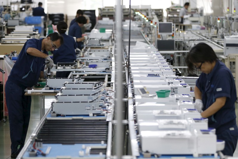 FILE PHOTO: Employees work an assembly line at a factory of Glory Ltd., a manufacturer of automatic change dispensers, in Kazo, north of Tokyo