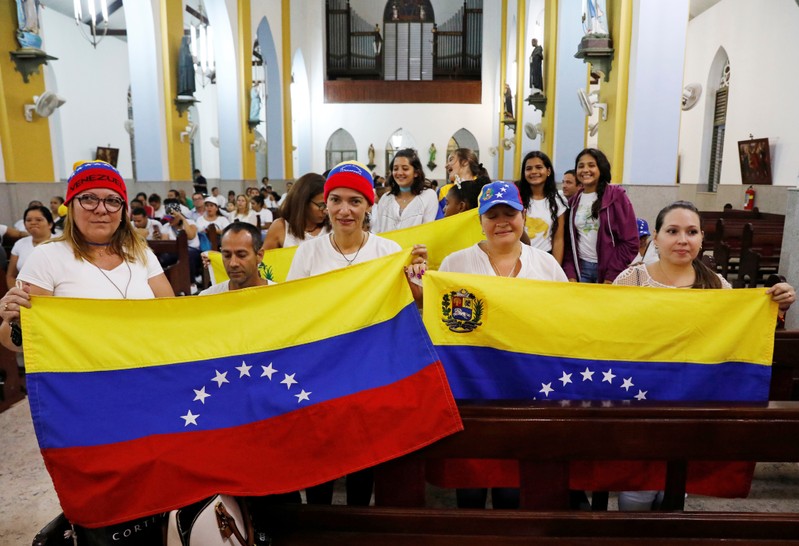 Supporters of Venezuela's opposition leader Juan Guaido hold Venezuelan flags during a meeting at the Queen of the Most Holy Rosary Cathedral in Willemstad on the island of Curacao