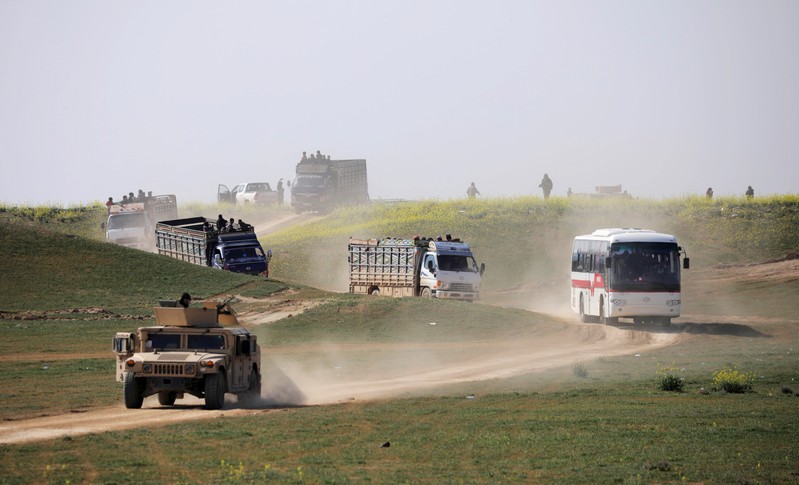 Trucks loaded with civilians ride near the village of Baghouz, Deir Al Zor province