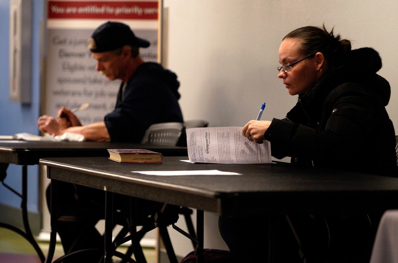 Job seekers fill out applications at a job fair at the Denver Workforce Center in Denver