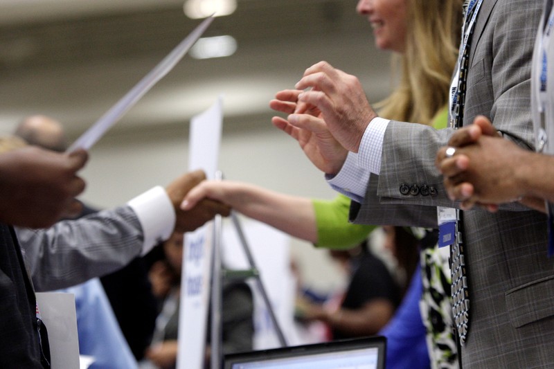 Corporate recruiters gesture and shake hands as they talk with job seekers at a Hire Our Heroes job fair targeting unemployed military veterans and sponsored by the Cable Show, a cable television industry trade show in Washington