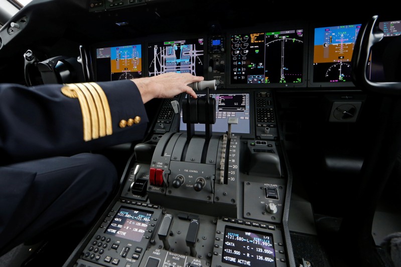 A pilot stands in the cockpit of a passenger aircraft