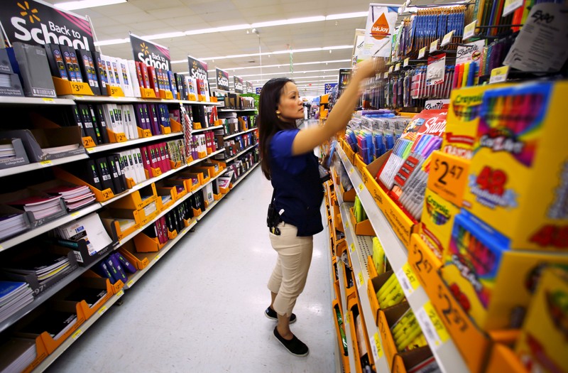 Walmart department manager Karren Gomes helps stock shelves with school supplies as the retail store prepare for back to school shoppers in San Diego, California