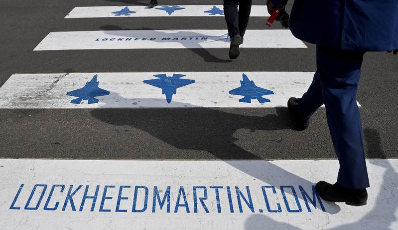 FILE PHOTO - Trade visitors are seen walking over a road crossing covered with Lockheed Martin branding at Farnborough International Airshow in Farnborough, Britain