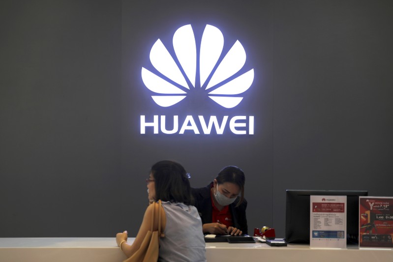 FILE PHOTO : A woman sits next to a salesperson at a Huawei shop in Bangkok, Thailand