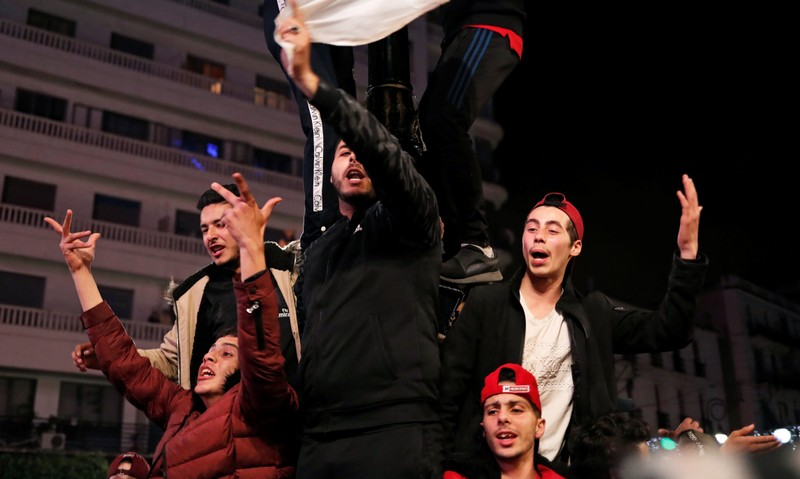 People celebrate on the streets after President Abdelaziz Bouteflika announced he will not run for a fifth term, in Algiers