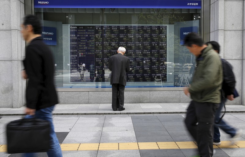 FILE PHOTO: Man looks at a stock quotation board outside a brokerage in Tokyo