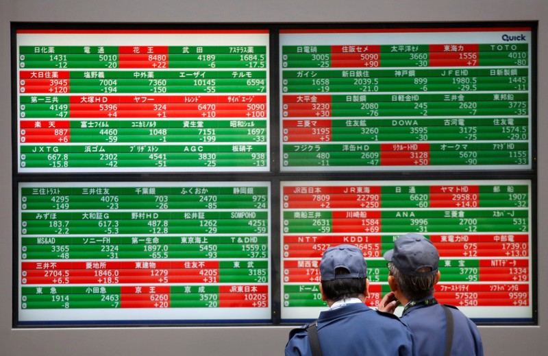 FILE PHOTO: Men look at stock quotation boards outside a brokerage in Tokyo