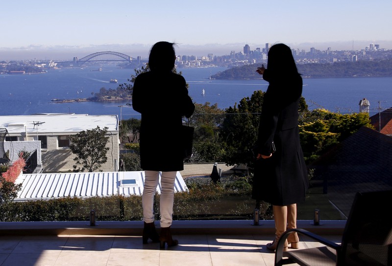 FILE PHOTO: The Sydney Opera House and Harbour Bridge can be seen behind a real estate agent and buyer in the Sydney suburb of Vaucluse, Australia