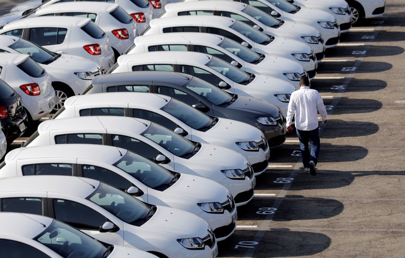 A person walks past cars at a parking lot in Sao Bernardo do Campo, Brazil