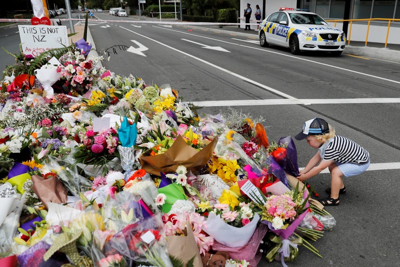 A boy places flowers at a memorial as a tribute to victims of the mosque attacks, near a police line outside Masjid Al Noor in Christchurch