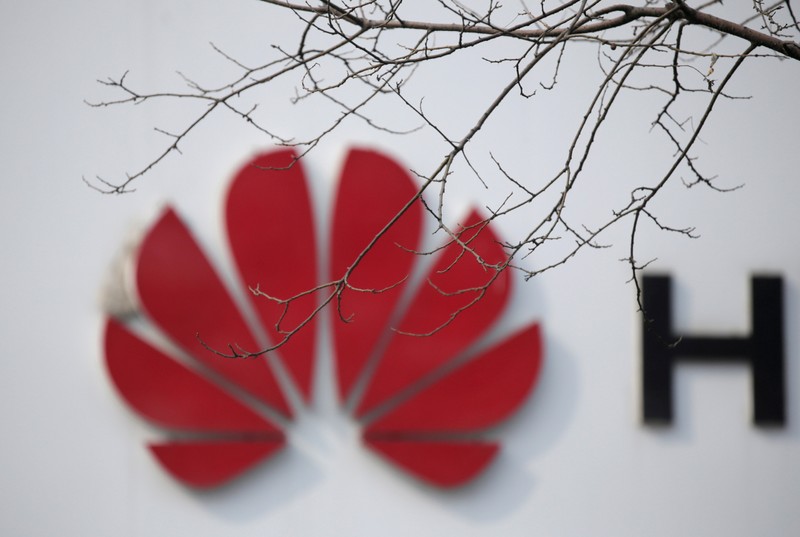 FILE PHOTO: A Huawei company logo is seen behind tree branches in Beijing