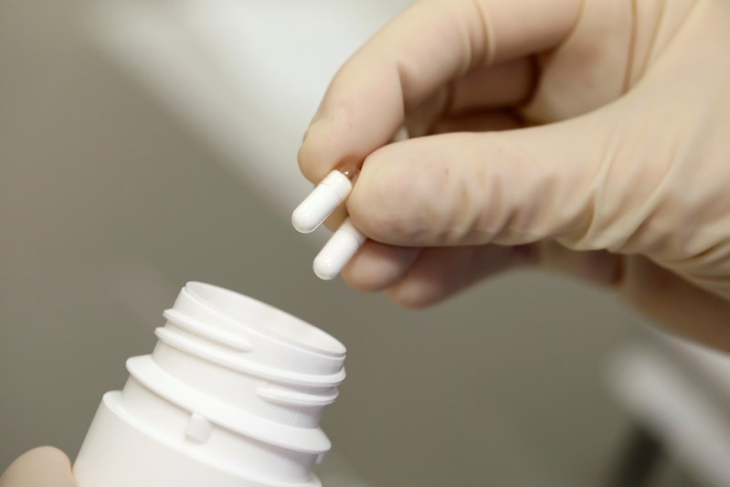 A pharmacy technician at the Amsterdam UMC hospital demonstrates a procedure for mixing and preparing a medicine and distributing it in capsules, in Amsterdam