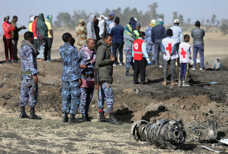 Ethiopian Federal policemen stand near engine parts at the scene of the Ethiopian Airlines Flight ET 302 plane crash, near the town of Bishoftu