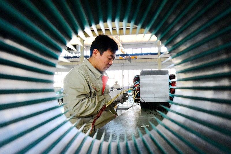 Man works on electric machine parts at a workshop of an equipment manufacturing company in Weifang, Shandong