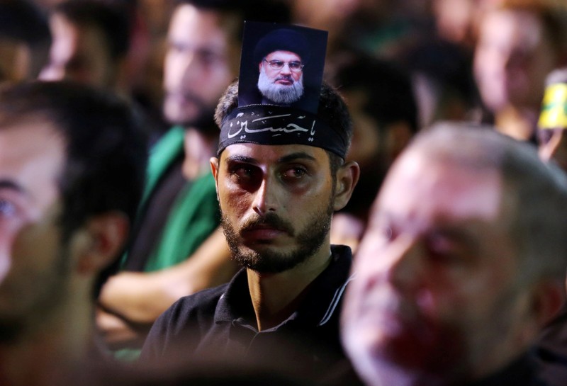 FILE PHOTO: A supporter of Lebanon's Hezbollah leader Sayyed Hassan Nasrallah has his picture on his head, during a live broadcast, the night before Muslim Shi'ites around the world mark the day of Ashura, in Beirut