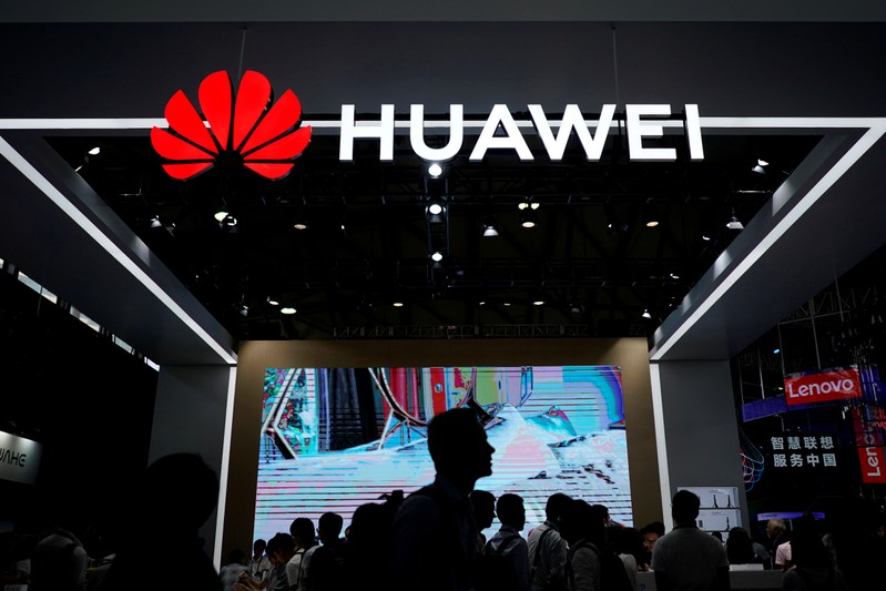 FILE PHOTO: People walk past a sign board of Huawei at CES (Consumer Electronics Show) Asia 2018 in Shanghai