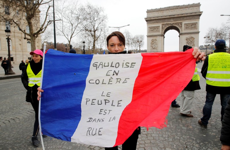 A protester holds the French flag on the Champs Elysees near the Arc de Triomphe during a demonstration by the 