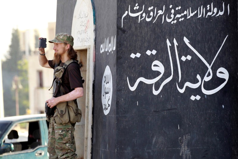 FILE PHOTO - A Militant Islamist fighter uses a mobile to film his fellow fighters taking part in a military parade along streets of Syria's northern Raqqa province