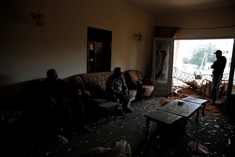 Palestinians sit inside their house that was damaged in a nearby Israeli air strike in Gaza City