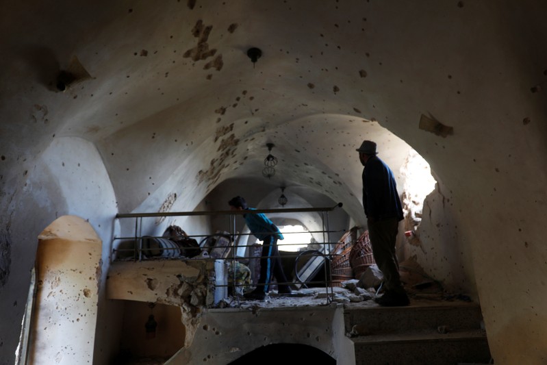Residents check a damaged house where a Palestinian gunman was killed by Israeli forces in the Israeli-occupied West Bank