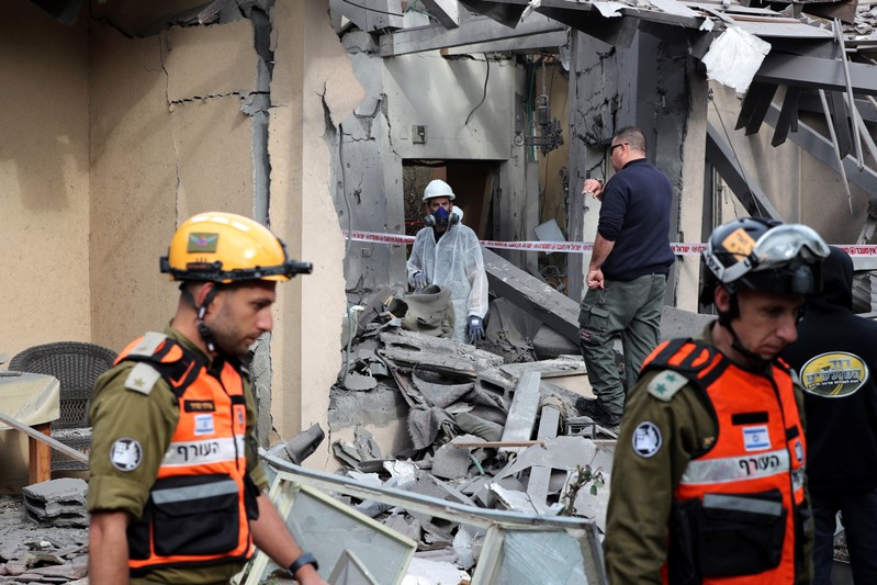 Israeli policemen and soldiers inspect a damaged house that was hit by a rocket north of Tel Aviv Israel
