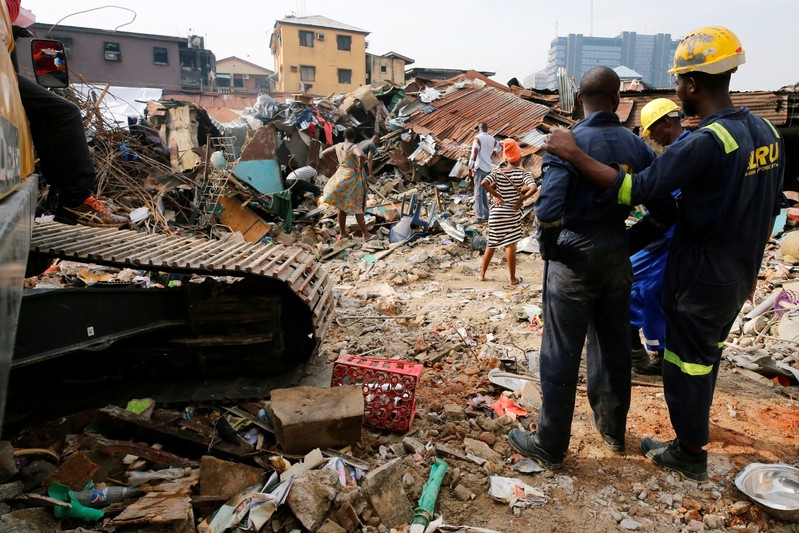 Rescuers are seen as people search for belongings at the site of a collapsed building in Nigeria's commercial capital of Lagos