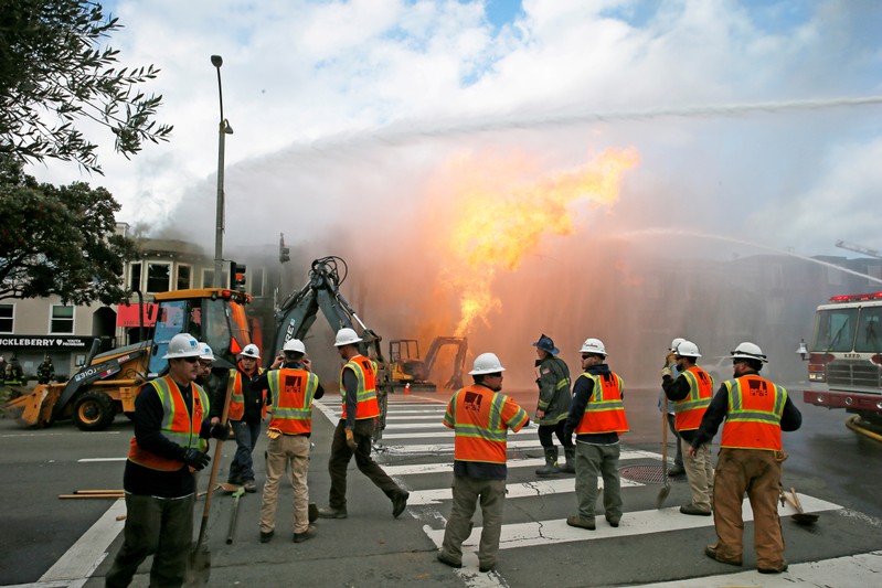 PG&E officials are seen as firefighters battle a fire following an explosion at Geary boulevard and Parker Avenue in San Francisco