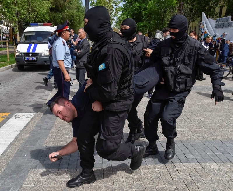 Policemen detain an opposition supporter during a protest rally in Almaty