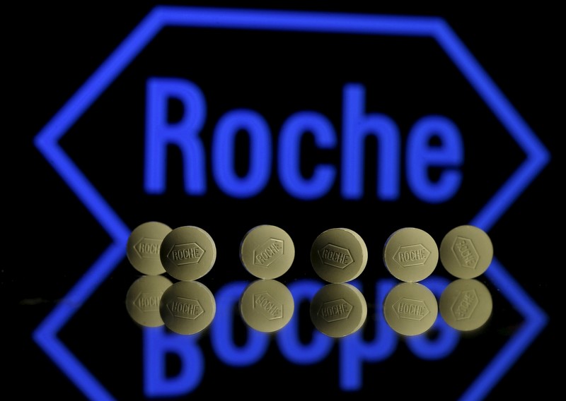 FILE PHOTO: Roche tablets are seen positioned in front of a displayed Roche logo in this photo illustration