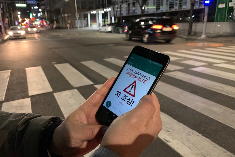 Kim Jong-hoon, a senior researcher at Korea Institute of Civil Engineering and Building Technology (KICT) demonstrates an application 'Watch Out' that gives an alert to a user distracted by using smart phone while crossing a zebra crossing, in Ilsan