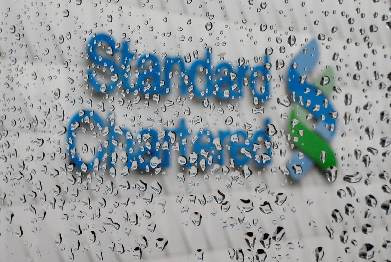 FILE PHOTO: A Standard Chartered logo at its headquarters is seen through a window with raindrops in Hong Kong