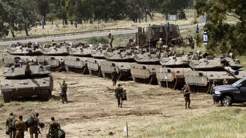 Israeli soldiers walk by Merkava Mark IV tanks during a military drill in the Israeli-annexed Golan Heights on May 1, 2018.