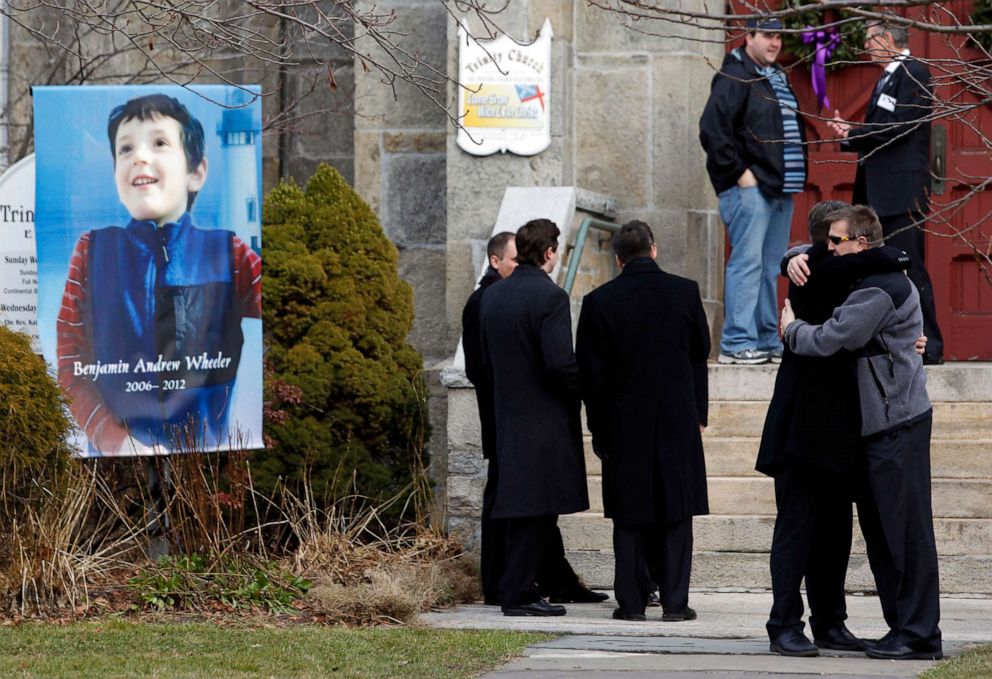 Mourners embrace outside of Trinity Episcopal Church while standing next to a portrait of Benjamin Andrew Wheeler, one of the students killed in the Sandy Hook Elementary School shooting, Dec. 20, 2012, in Newtown, Conn.