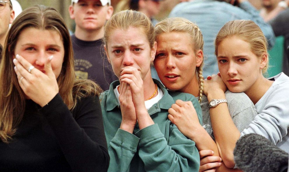Students from Columbine High School in Littleton, Colo., watch as the last of their fellow students are evacuated from the school building following a mass shooting at the school on April 20, 1999.