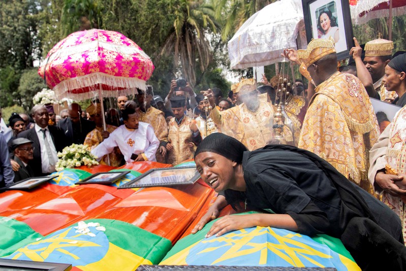 A woman mourns next to coffins during the burial ceremony of the Ethiopian Airline Flight ET 302 crash victims at the Holy Trinity Cathedral Orthodox church in Addis Ababa