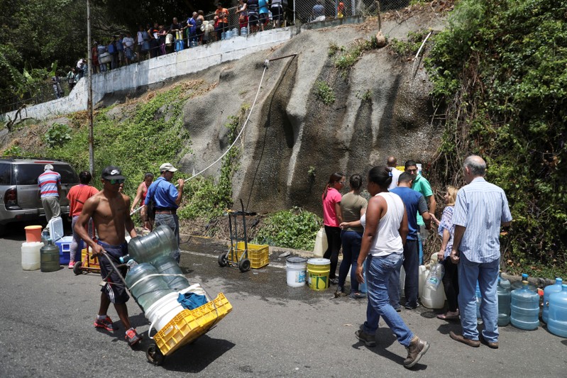 People collect water from a river in Caracas
