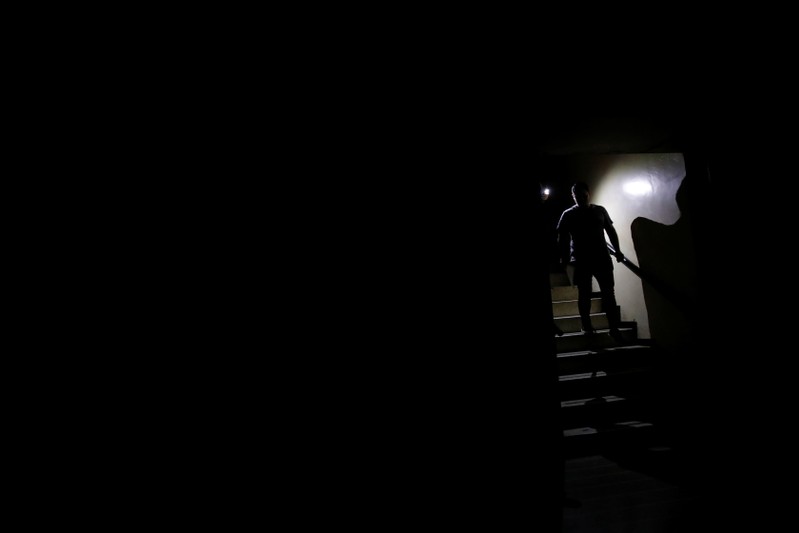 People use light from phones while they walk at the staircase of a building during a blackout in Caracas