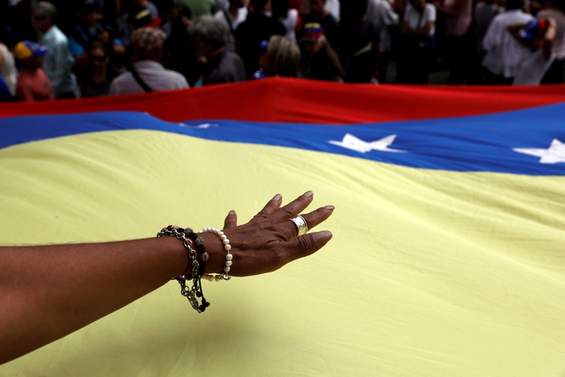 A hand is seen over the national flag during a protest against Venezuelan President Nicolas Maduro's government in Caracas