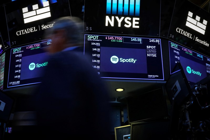 A trader passes by screens showing Spotify on the floor at the NYSE in New York