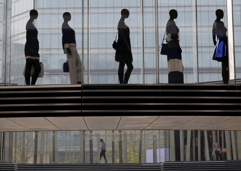 A man is seen walking under mannequins at a shopping mall in Beijing