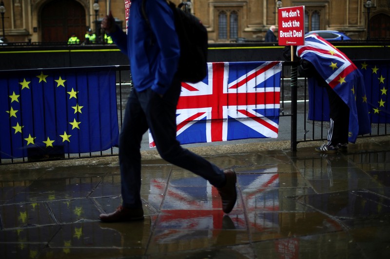 Person walks past an EU and a British flag in London